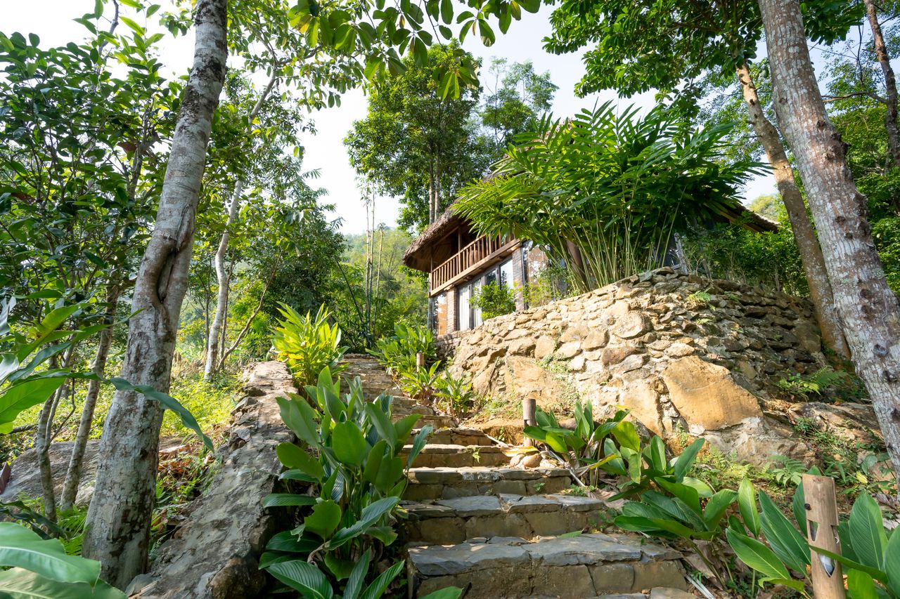 services-02 Low angle of small hotel with long outdoor stone stairs located on top of green hill in tropical resort